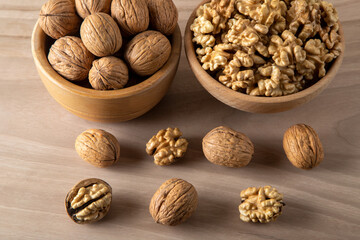 Bowl of walnuts and whole walnut kernels on wooden background,top view