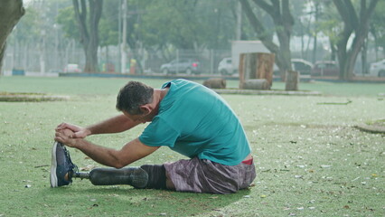One disabled man with prosthetic leg stretching outside after sport