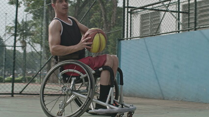 One disabled basketball player playing ball outside. Closeup of paraplegic person on wheelchair action motion. Sport and disability concept