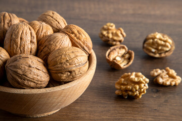 Bowl of walnuts and whole walnut kernels on wooden background,top view