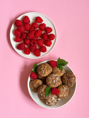 Gingerbread flavored gingerbread in a white bowl with raspberries, next to a plate with raspberries on a pink background. Vertical arrangement.