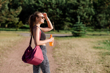 Obraz premium Slim fit woman walking with a big sports bag outdoors in the park