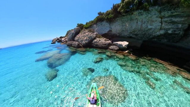 Aerial view kayak in the cliffs and cave of Petit Sperone beach, close to the Bonifacio town in Corsica of France. Drone view of woman kayaking in the Mediterranean sea by Piana island.