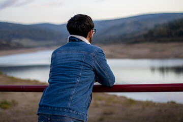 Fototapeta na wymiar portrait of an unrecognizable young man with glasses with his back turned contemplating the landscape