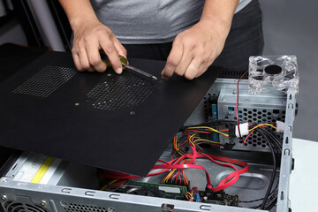 Technician removing the screw from the leg of a desktop PC