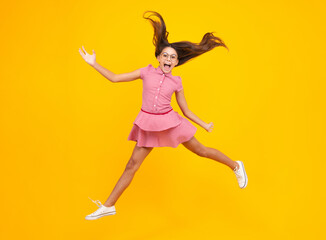 Amazed teen girl. Excited expression, cheerful and glad. Full length cheerful teenager kid jump enjoy rejoice win isolated on yellow background. Small child girl in summer dress jumping.