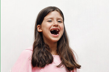 Caucasian girl schoolgirl emotionally opened her mouth and laughs in a pink poncho towel on a white background, light, space