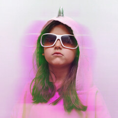 a little girl in a pink poncho and sunglasses is very serious, a funny child in a unicorn costume...