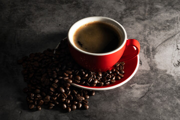 Obraz na płótnie Canvas Hot espresso in red coffee mug with coffee beans on concrete