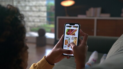 Hand closeup browsing food online store on cellphone app. Person scrolling screen choosing meal on menu