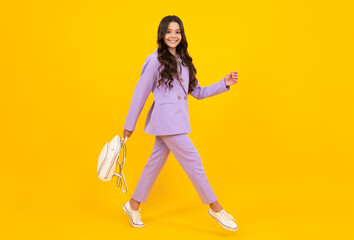 Fototapeta na wymiar School girl in school uniform with school bag. Schoolchild teenager hold backpack on yellow isolated background. Happy face, positive and smiling emotions of teenager girl.