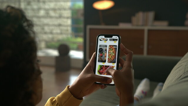 Person Using Online Delivery menu phone. Woman Orders at Food Home In Online Store using smartphone on delivery app. Woman at Home Lying on Couch in Living Room