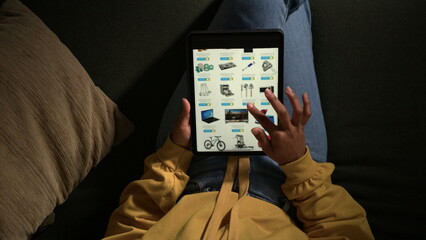 Person browsing online store on tablet. Top angle view of girl closeup hands holding device searching for product. Shopping online