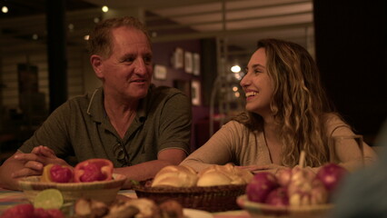 Friends and family in conversation at night sitting at table in backyard