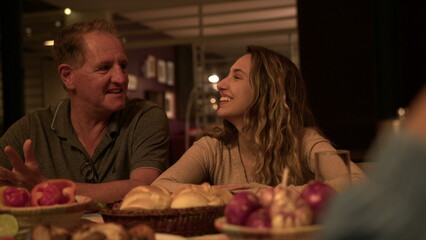 Friends and family in conversation at night sitting at table in backyard