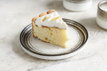 Slice of Homemade Coconut Buttermilk Pound Cake glazed whipped cream and coconut flakes on gray concrete background. Selective focus