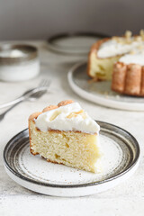 Slice of Homemade Coconut Buttermilk Pound Cake glazed whipped cream and coconut flakes on gray concrete background. Selective focus