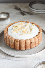 Homemade Coconut Buttermilk Pound Cake glazed whipped cream and coconut flakes on gray concrete background. Selective focus