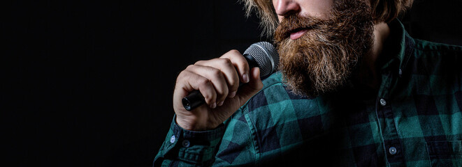 Bearded man in karaoke sings a song into a microphone. Male attends karaoke. Man with a beard...