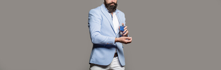 Masculine perfume, bearded man in a suit. Male holding up bottle of perfume. Man perfume,...