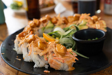 Sushi roll plate with breaded prawn and sauce on top. Traditional Japanese food by Mexican style concept