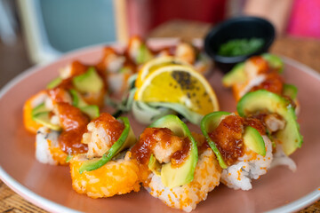 California sushi roll plate with avocado, prawn and spicy sauce on top. Gourmet food restaurant concept