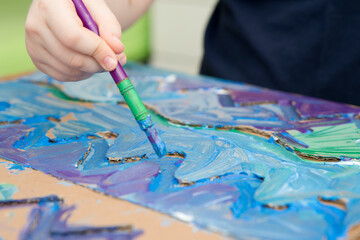 Zero waste. Corrugated cardboard cut and glued to make terrain. boy painting it to look like sea. DIY games at home. save the ocean concept.
