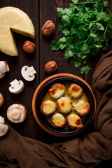 Traditional Georgian dish, appetizer, stuffed mushrooms, Sulguni cheese, baked in a Ketzi clay pan, on a wooden table, close-up, no people,