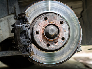 Closeup weared overheated brake disk and detail of wheel hub. Replacing brake pads in car service