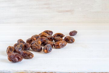 Date fruit on white wooden background.