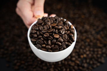 Close-up of a cup of flavored coffee. A barista holds out fresh natural coffee to a customer. The concept of making natural coffee. Selective focus.