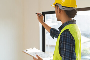 Asian inspector checking structure of new property and taking note in the clipboard for review and...