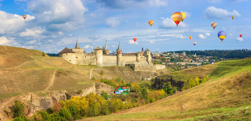 Autumn landscape - view of a medieval fortified castle on a hill with flying the hot air balloons,...