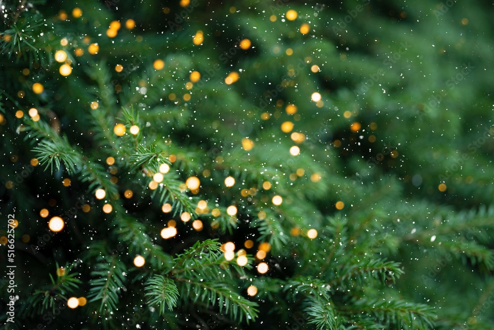 Wall mural christmas tree branches with a garland against falling snow.