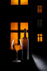 Still life with a glass and a bottle on the background of a glowing window