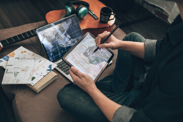 Travelers planning trips and use tablet to book hotels, buy plane tickets, search map, or find travel routes on sofa bed in living room at home. Travel concept.