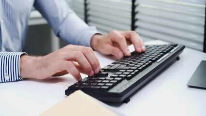 Close-up or closeup shot of Caucasian male employee's hand typing on keyboard to work with business agreement at his office table. White businessman with leadership skill negotiating with customers.