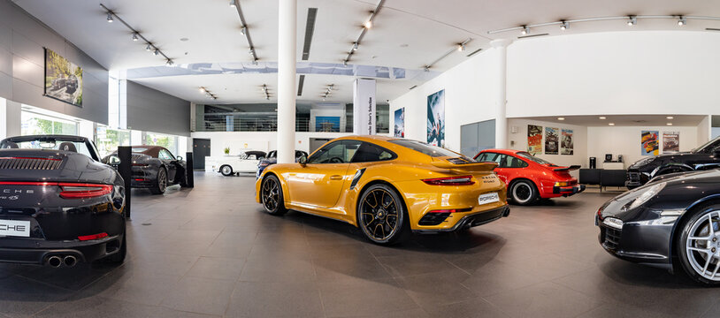 Matosinhos, Portugal - June 25, 2022: A picture of a Porsche dealership with an orange 911 Turbo S in the center.