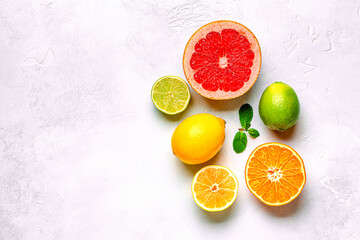 Fresh lemon, orange, grapefruit, lime, green leaves on light background, top view.