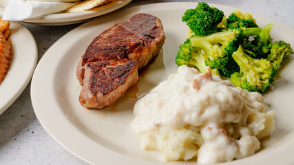Country grill steak served with mashed potatoes and gravy, and broccoli close up