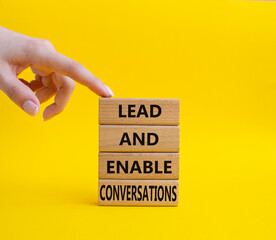 Lead and enable conversations symbol. Concept words Lead and enable conversations on wooden blocks. Beautiful yellow background. Business concept. Businessman hand. Copy space