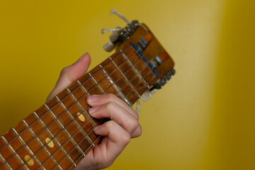 Pinch a chord on the guitar neck with your fingers on a yellow background