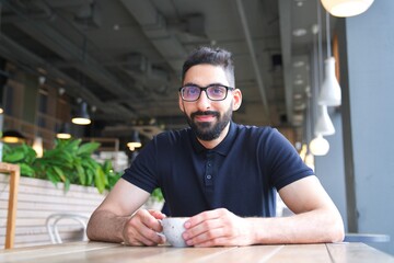 Portrait of happy positive Arab Muslim ethnic guy in glasses, young bearded man with black beard is...