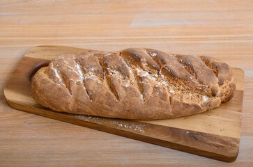Handmade home stile delicious fresh bread just cooked at farm house, prepared to be eaten at the wooden craft texture surface of the table, lies on a wooden board. No people studio professional photo
