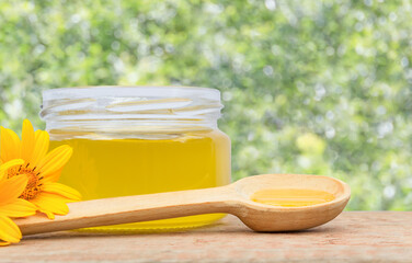 A small jar of honey with a wooden spoon on a wooden bar, copy space