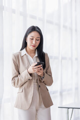 Portrait of Asian business woman using mobile phone application and pointing finger to smartphone isolated over white background.