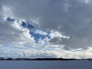 Multilayer cumulus clouds in the sky over a snowy plain.