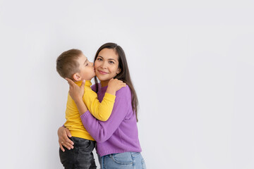 Happy young mother with her little son in love on a white background. son kisses mother. The concept of a happy family, motherhood. mother and child portrait