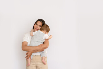 Happy young mother with her baby, little son in love on white background copy space. The concept of a happy family, motherhood. mother and child portrait