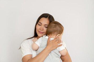 Happy young mother with her baby, little son in love on a white background. The concept of a happy...
